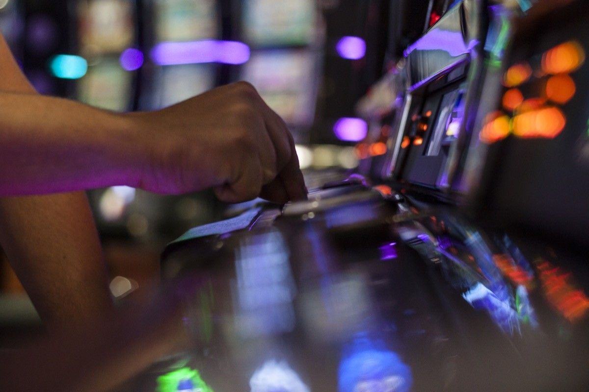 Adult Man Playing on Slot Machine in casino.