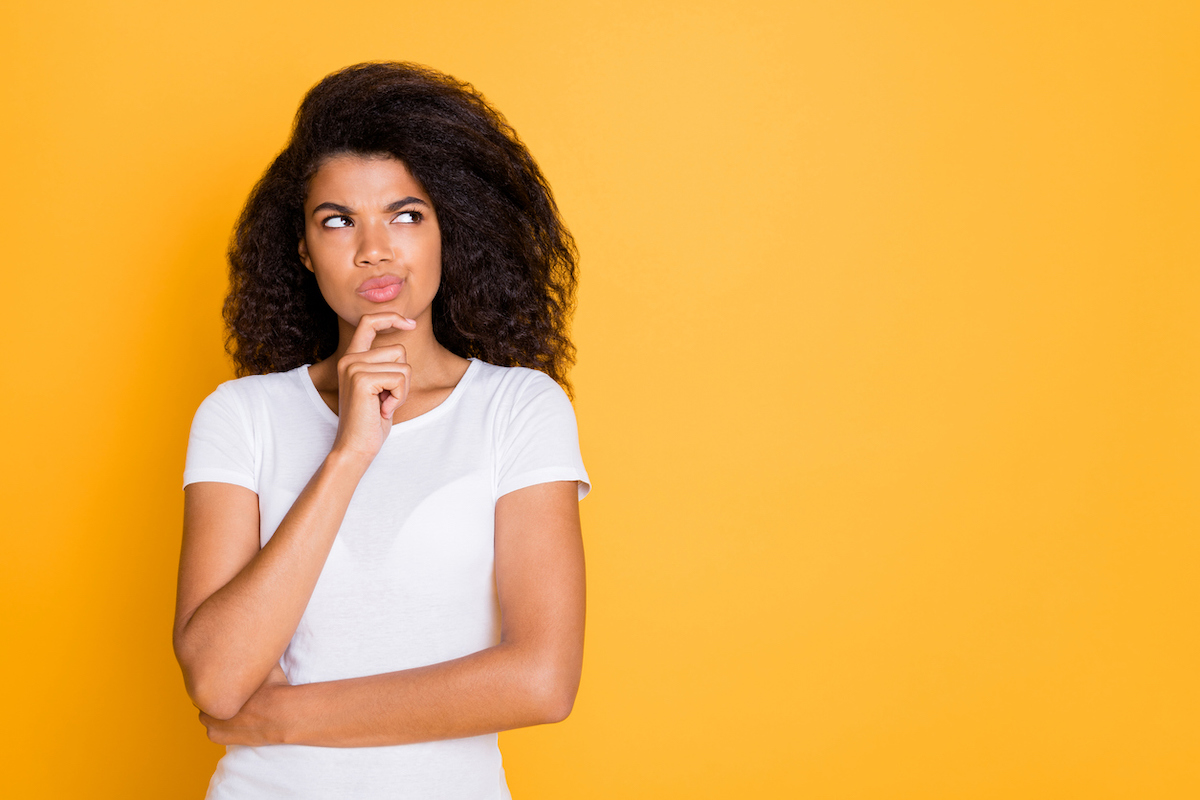 Photo of a pensive young woman wearing a white t-shirt against a yellow background.