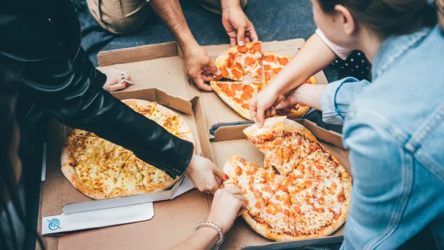 A group of people eating delivery pizza from boxes