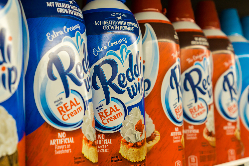 Cans of Reddi Wip whipped cream on the shelf at a store