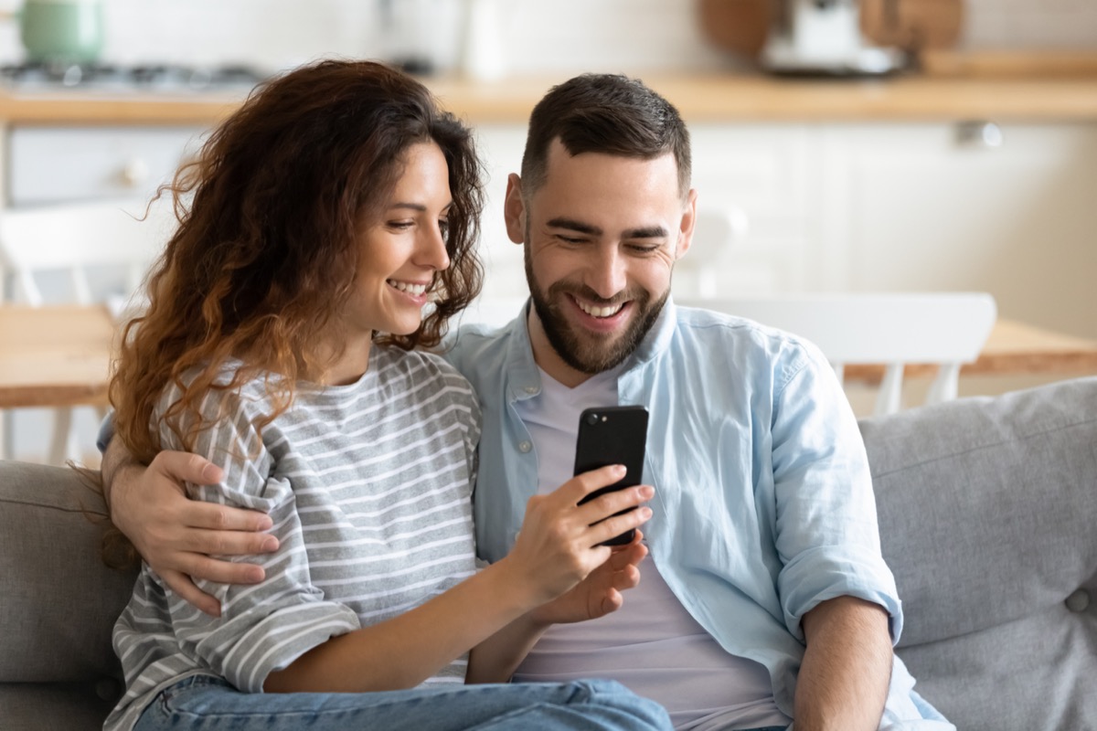 Two People Smiling and Looking at a Phone