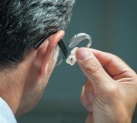 man putting hearing aid in