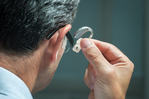 man putting hearing aid in