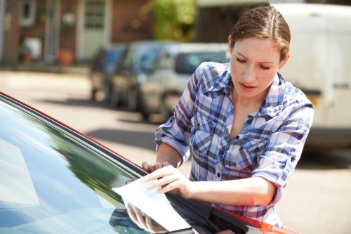 woman finding parking ticket on car