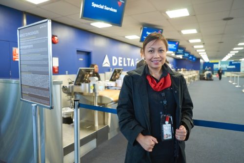 delta flight attendant standing in front of check-in at the airport