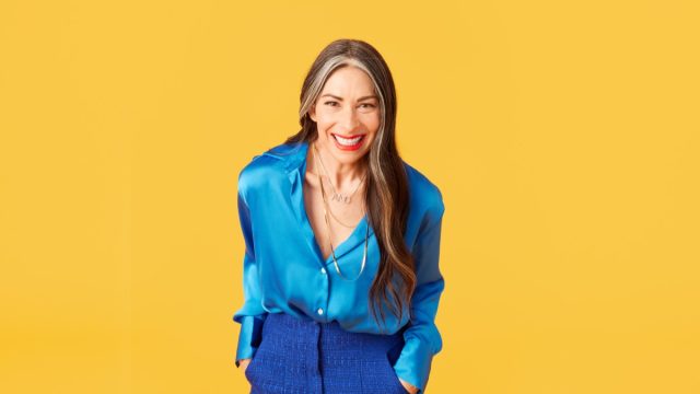 stacy london against a bright yellow background