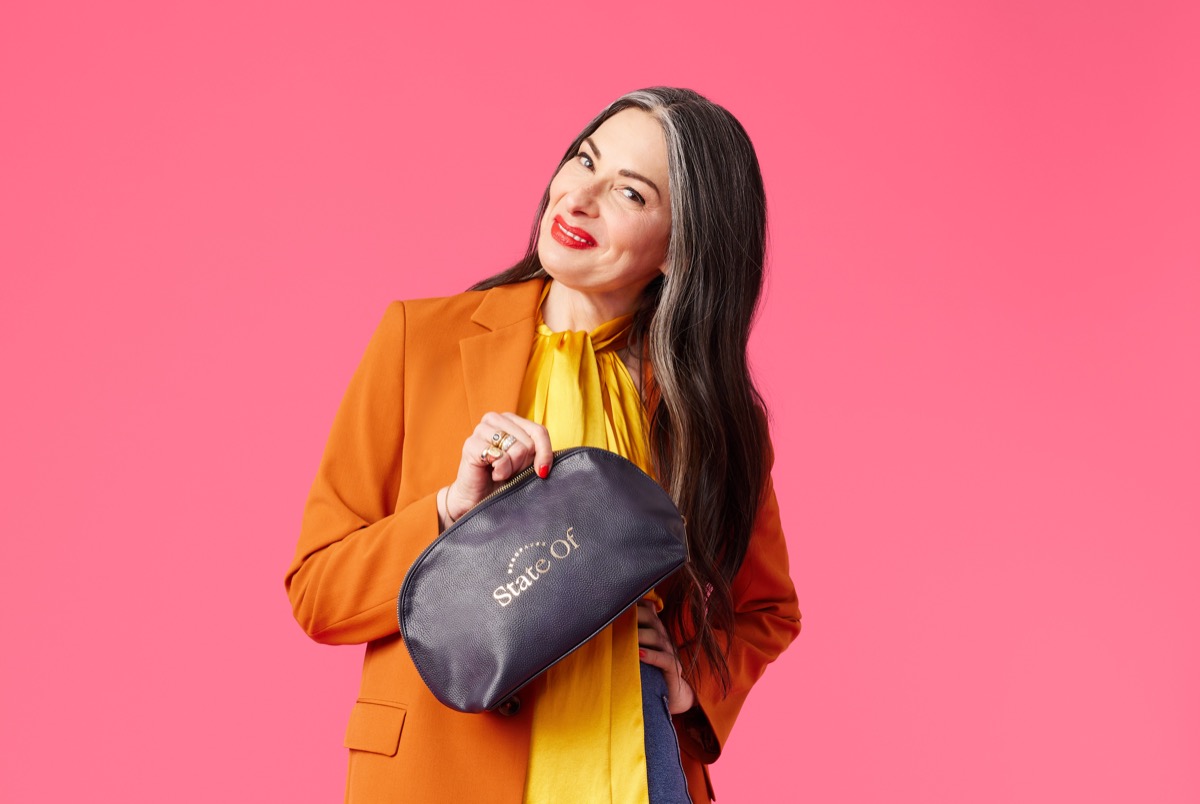 stacy london holding state of menopause bag against hot pink background