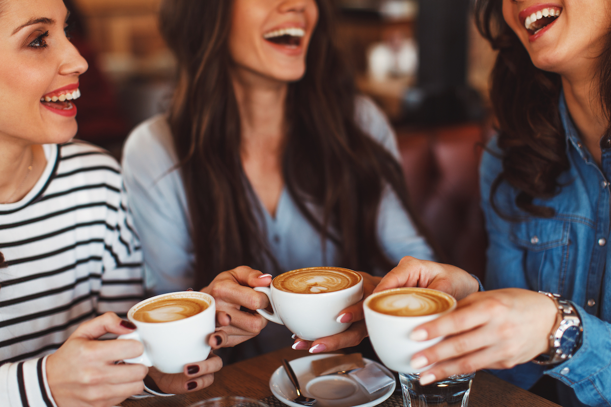 Three young women enjoy coffee at a coffee shop