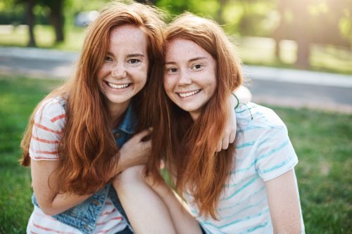 Portrait of identical ginger twin sisters smiling and having fun.