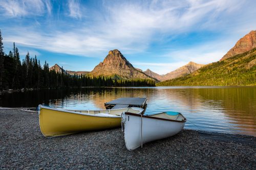 Glacier National Park's Two Medicine Lake at dawn, with kayaks sitting on the shore.