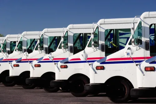 A row of US Postal service trucks, parked waiting to deliver the mail.
