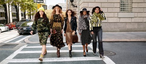 Four young women walking down a city street in fashionable clothes, marketing Walmart's Scoop clothing line.
