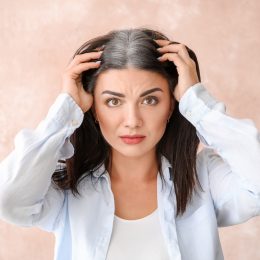 A stressed looking young woman exposing her gray roots in her hair.