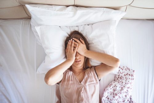 woman on bed having headache / insomnia / migraine / stress.