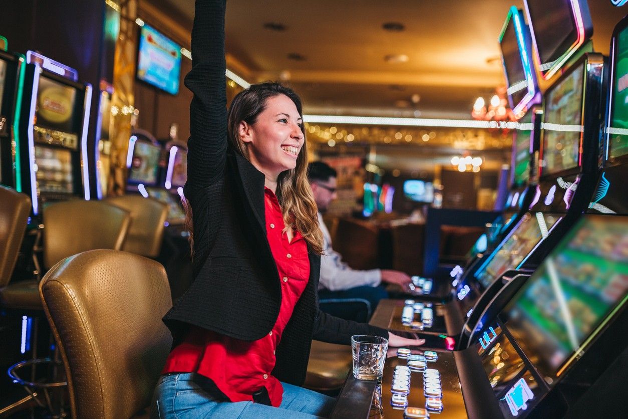 A young woman celebrates after winning a slot machine in a casino