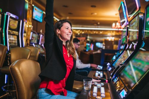 A young woman celebrating after winning a slot machine in a casino