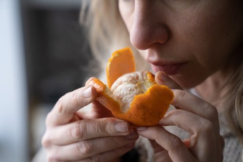 Woman trying to sense smell of fresh tangerine orange