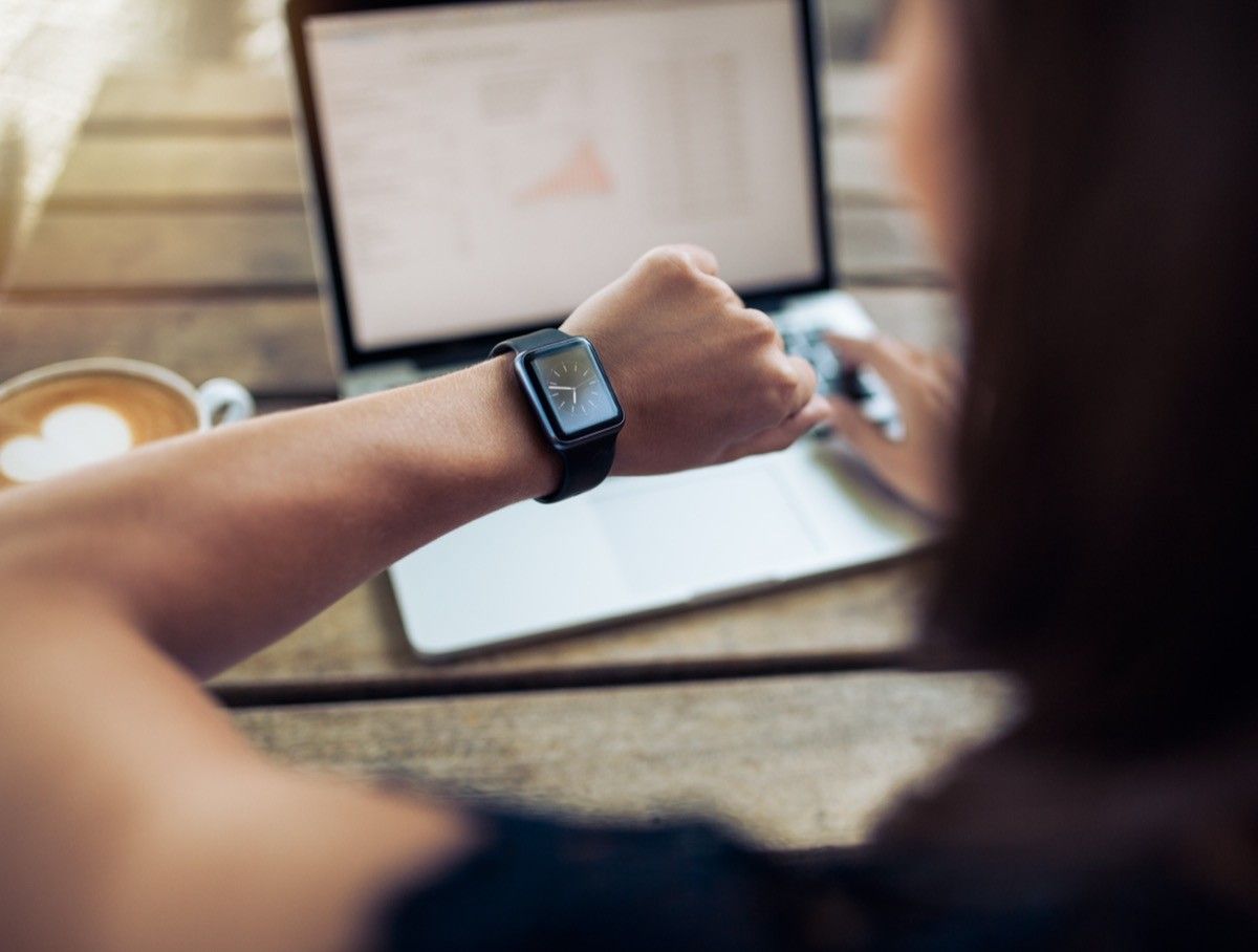 Primer plano de una mujer revisando la hora en su reloj inteligente. 