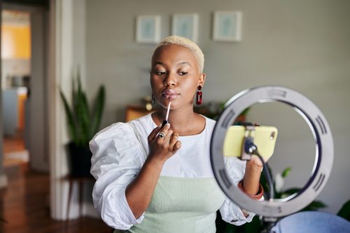 young black woman applying lipstick