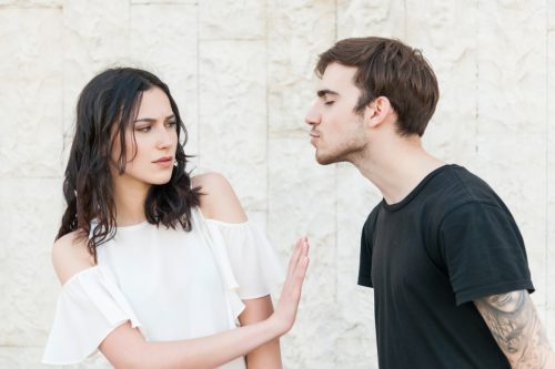 woman rejecting man trying to kiss her
