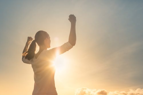 woman outside in sunlight with arms in the air