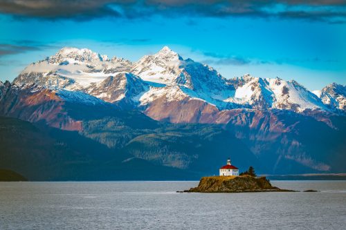 View of the Eldred Rock Lighthouse, a historic lighthouse adjacent to Lynn Canal in Alaska. It is the end of October with fresh snow on the mountains in the background.