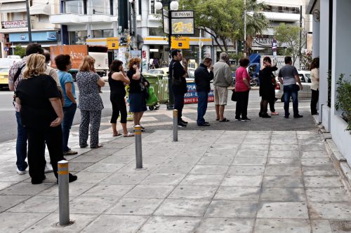 People line up outside a bank branch to use ATM machine