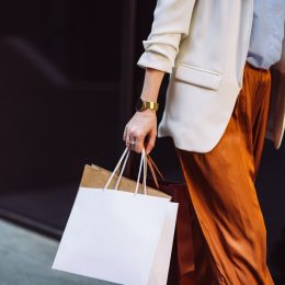 Unrecognizable businesswoman carrying paper bags while walking at the city street.