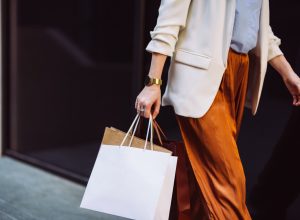 Unrecognizable businesswoman carrying paper bags while walking at the city street.