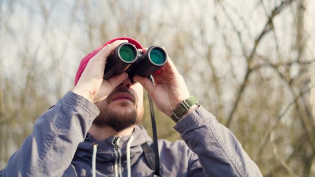 A man using binoculars while bird watching