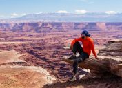 A hiker sitting on a rock ledge at Canyonlands National Park