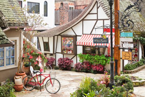 A streetscape in Carmel-by-the-Sea featuring a retail shop housed in a typical fairytale cottage - style architecture. 