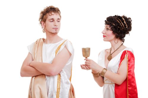 Couple dressed up as Greek gods against a white background.