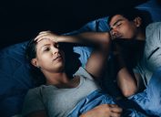Annoyed woman lying awake in bed with snoring boyfriend at home in the bedroom