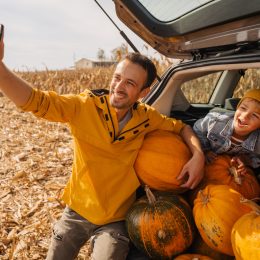 Photo of a young father and his sons taking pictures in a car trunk full of pumpkins