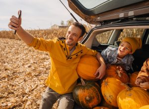 Photo of a young father and his sons taking pictures in a car trunk full of pumpkins
