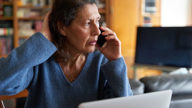 Stressed senior businesswoman on the phone while working on laptop