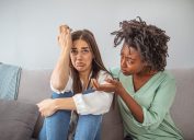 Young lady sharing her problem with friend. female in depression. Woman omforting hes sad friend sitting on a couch in the living room at home