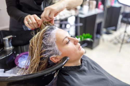 Woman having her hair washed at hair salon with highlights around her face.