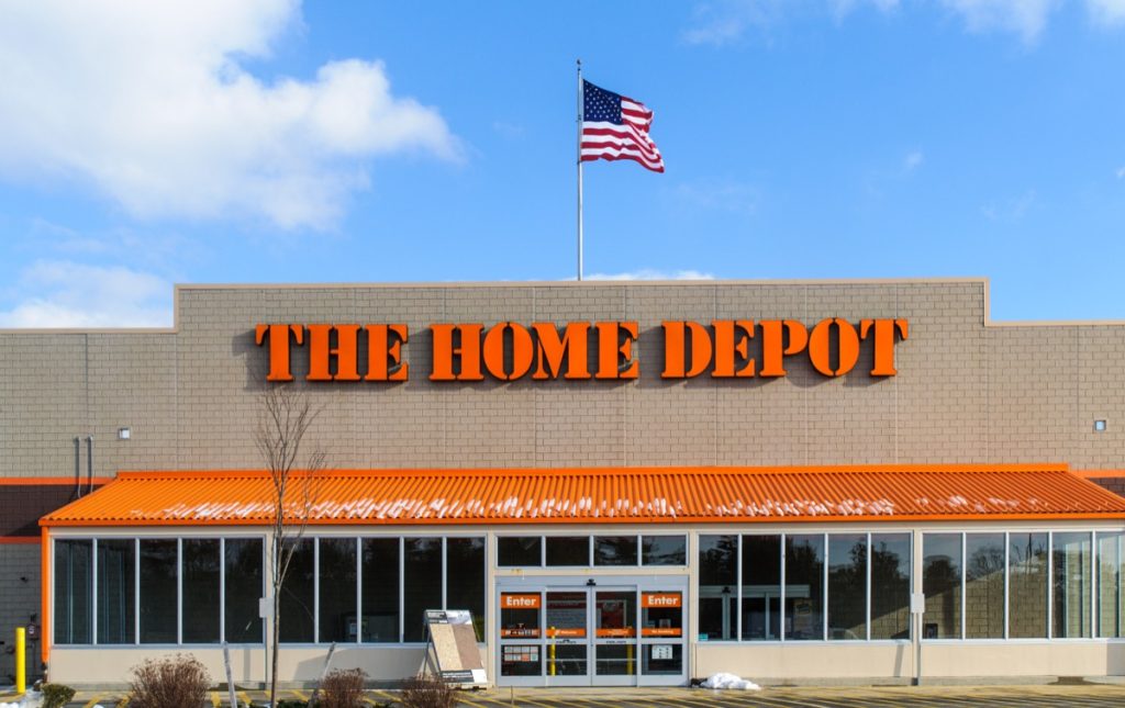 An American flag flies over the entrance and outside facade of a large Home Depot store that sells a full range of building matrerials