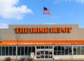 An American flag flies over the entrance and outside facade of a large Home Depot store that sells a full range of building matrerials