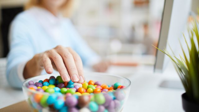 Close-up of woman's hand reaching into candy bowl.