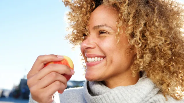 Close up side portrait of healthy young african american woman holding apple