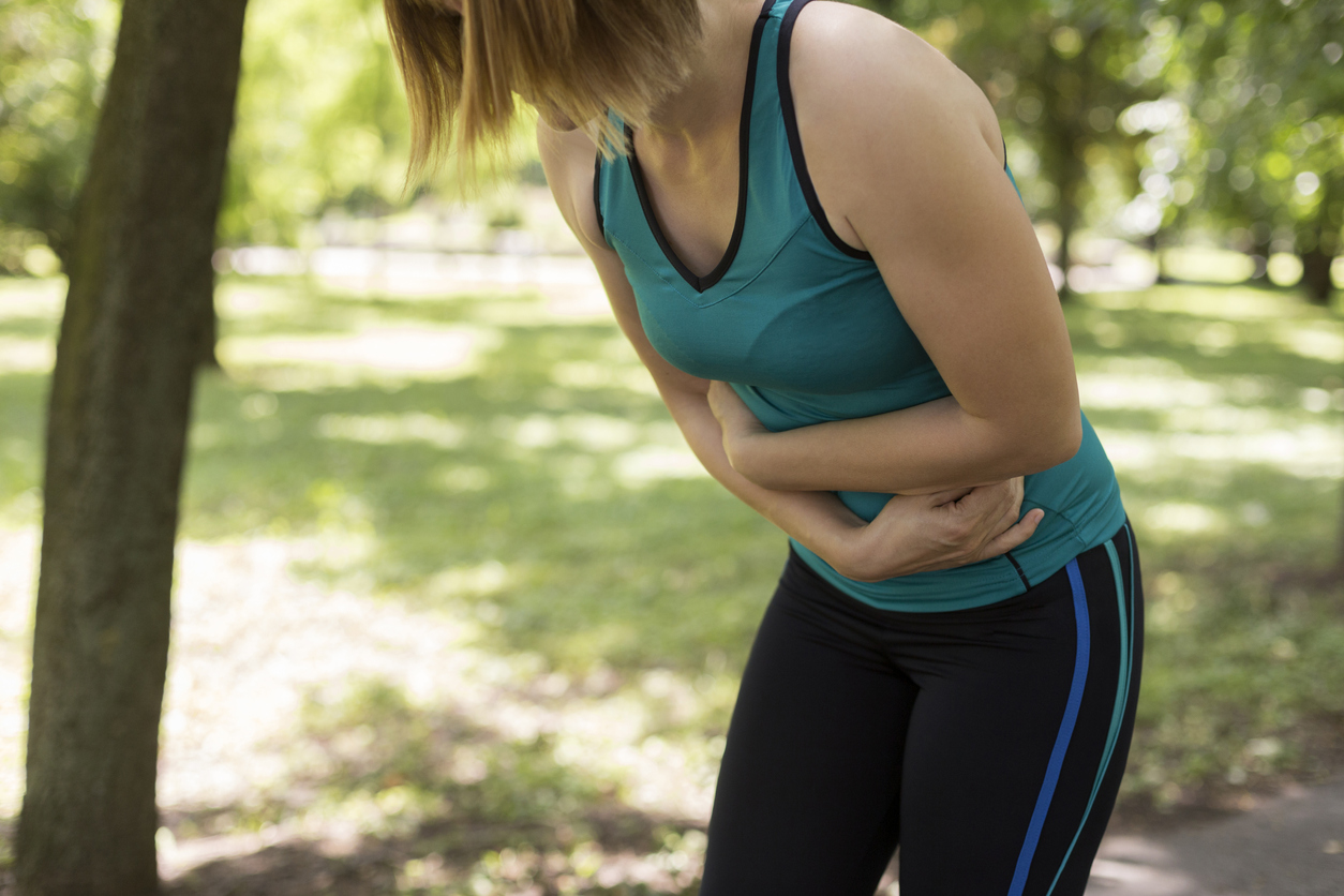 Woman in exercise clothes holding her stomach.