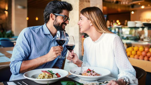Romantic couple enjoying lunch in the restaurant, eating paste and drinking red wine. Lifestyle, love, relationships, food concept