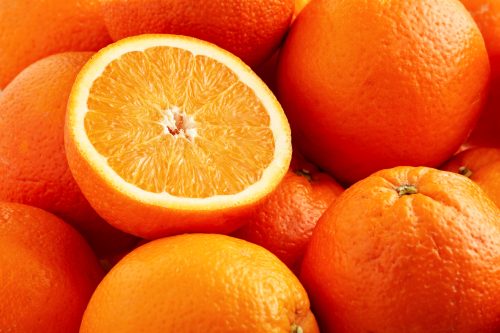 Heap of fresh oranges with one half slice.