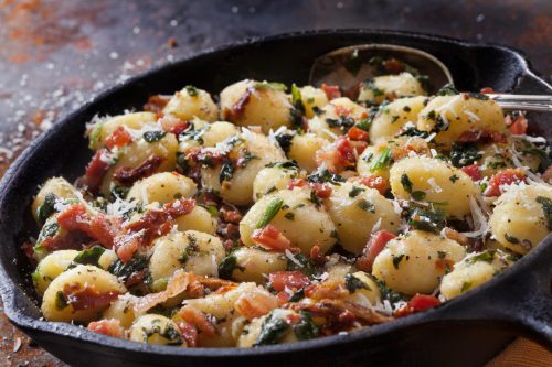 Gnocchi mit knusprigem Pancetta, sonnengetrockneten Tomaten, Spinat und Parmesankäse in brauner Buttersauce