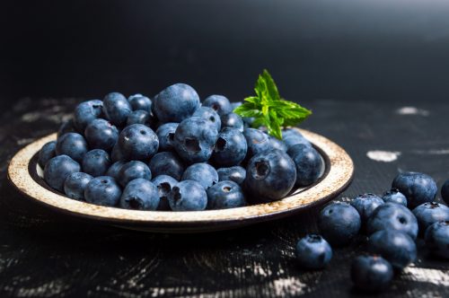 Fresh blueberry fruit on a plate on dark background