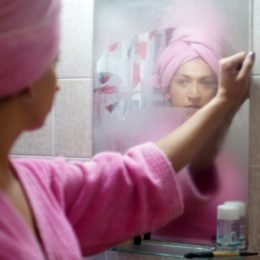Woman looking at herself in bathroom mirror.