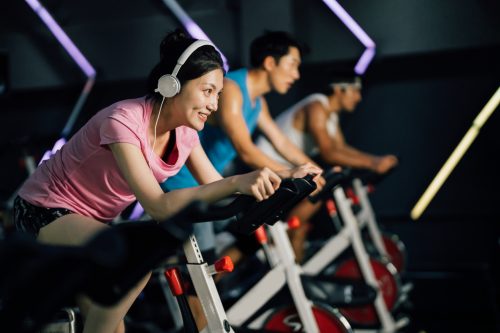 Asian young woman cycling on an exercise bike at gym.